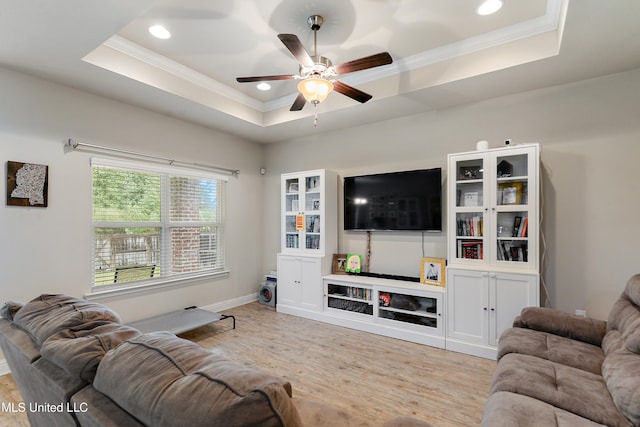 living room with ceiling fan, a raised ceiling, light hardwood / wood-style flooring, and crown molding