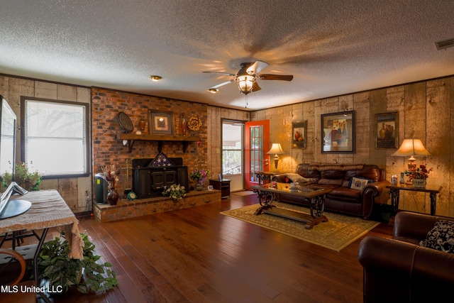 living room featuring hardwood / wood-style flooring, a textured ceiling, ceiling fan, and a wood stove