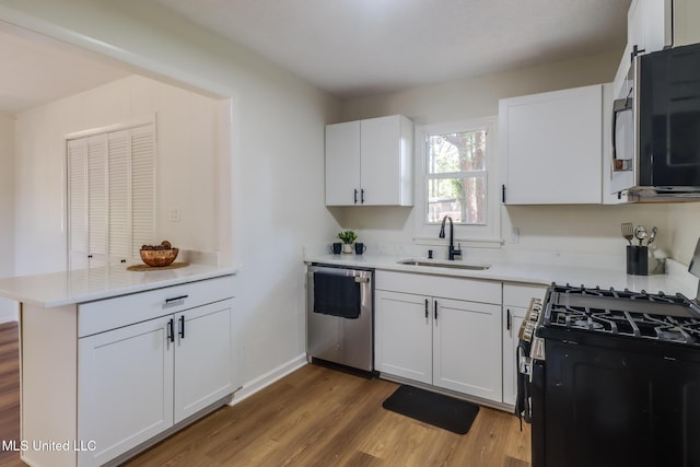 3217 Detroit Ave, Pascagoula, MS 39581 - kitchen with appliances with stainless steel finishes, a sink, a peninsula, wood finished floors, and light countertops
