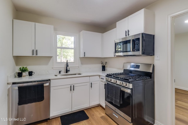3217 Detroit Ave, Pascagoula, MS 39581 - kitchen featuring appliances with stainless steel finishes, a sink, light wood-type flooring, white cabinets, and light countertops