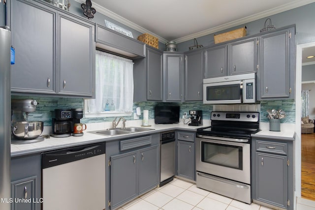 kitchen featuring stainless steel appliances, a sink, backsplash, and crown molding