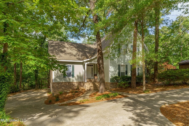 view of front of home featuring concrete driveway, brick siding, and a shingled roof