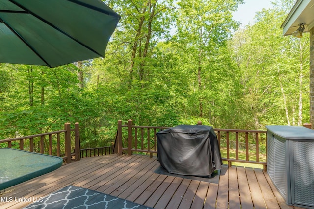 deck with grilling area and a forest view