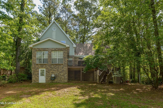 rear view of house featuring stairway, a wooden deck, brick siding, and a yard