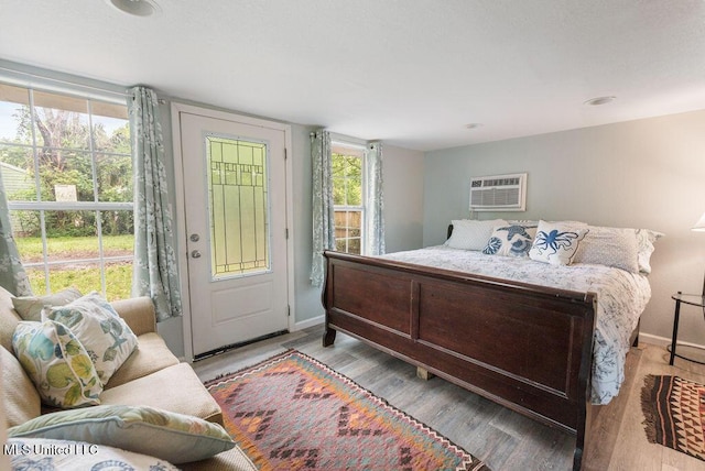 317 Ballentine St, Bay Saint Louis, MS 39520 - bedroom featuring a wall mounted air conditioner, baseboards, multiple windows, and wood finished floors