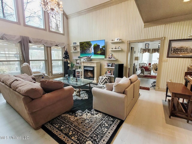 living room with ornamental molding, light hardwood / wood-style flooring, high vaulted ceiling, and a notable chandelier