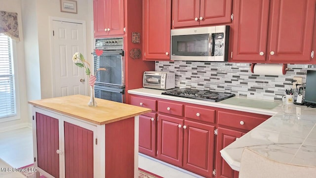 kitchen with backsplash, light stone counters, a kitchen island, and black appliances