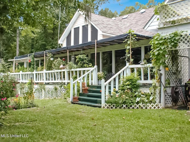 rear view of property with a wooden deck, a sunroom, and a yard