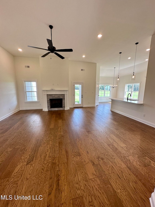 unfurnished living room with ceiling fan, a wealth of natural light, a tile fireplace, and hardwood / wood-style floors