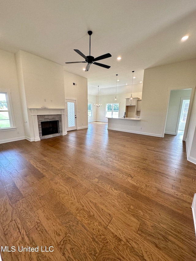 unfurnished living room with dark hardwood / wood-style flooring and ceiling fan with notable chandelier