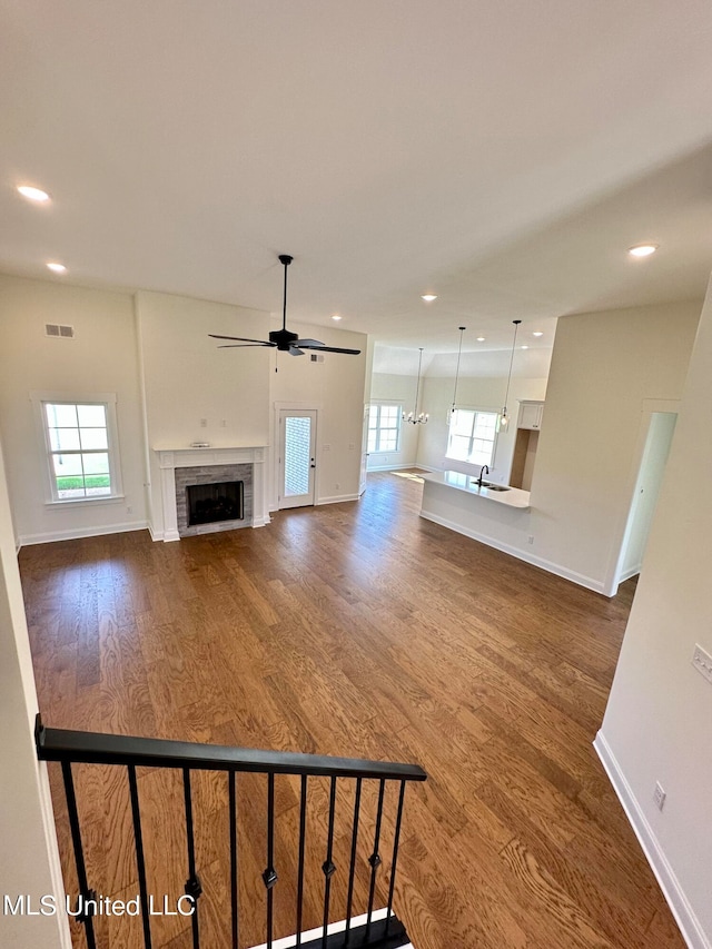 unfurnished living room featuring ceiling fan, a healthy amount of sunlight, a fireplace, and hardwood / wood-style floors