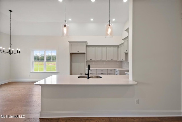 kitchen featuring backsplash, hanging light fixtures, sink, and dark hardwood / wood-style flooring