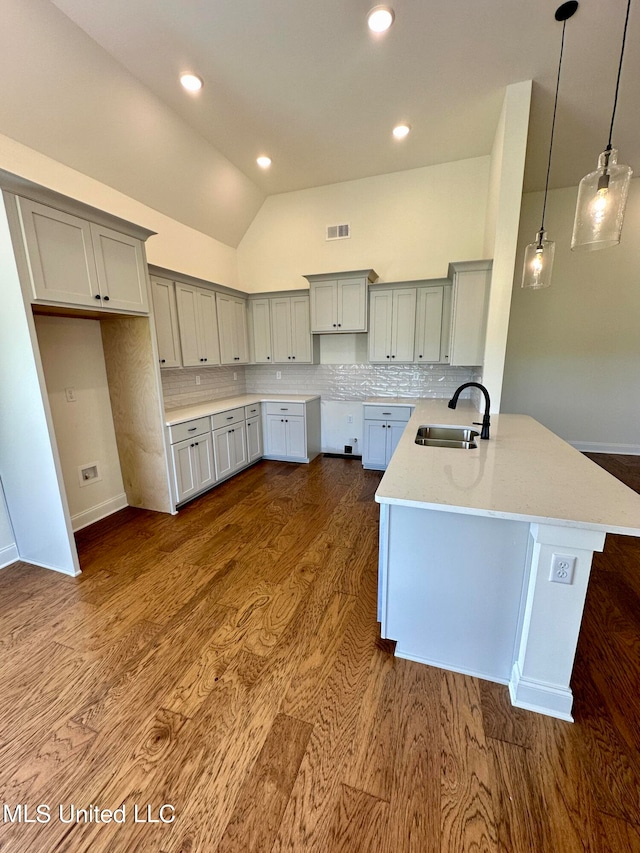 kitchen with lofted ceiling, hanging light fixtures, sink, and dark wood-type flooring