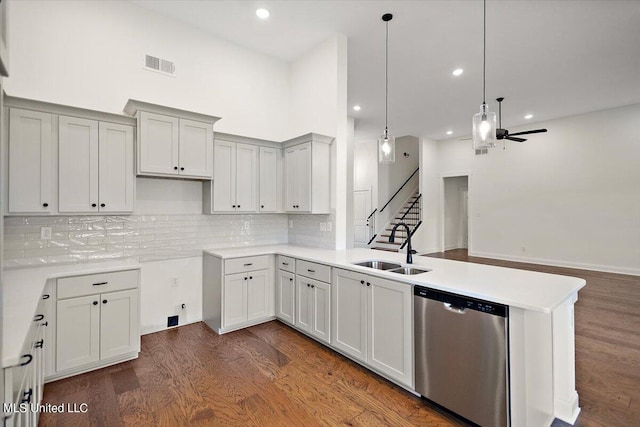 kitchen featuring ceiling fan, stainless steel dishwasher, dark wood-type flooring, a towering ceiling, and sink