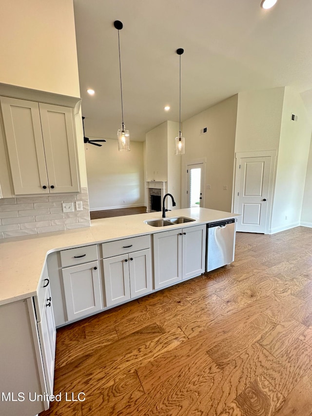 kitchen with white cabinets, backsplash, stainless steel dishwasher, light hardwood / wood-style floors, and sink