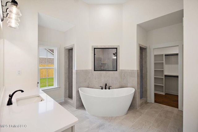 bathroom with vanity, plus walk in shower, tile walls, and tile patterned flooring