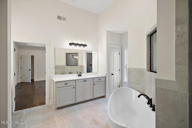 bathroom with vanity, tile walls, wood-type flooring, and a bathtub