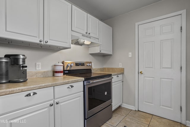 kitchen with electric range, light tile patterned flooring, light countertops, white cabinets, and under cabinet range hood