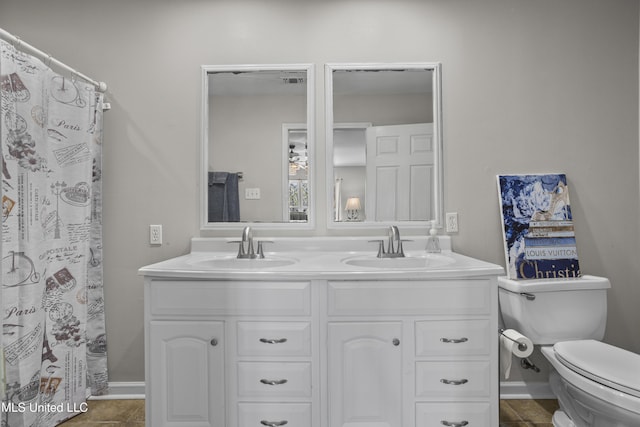 full bathroom featuring a sink, baseboards, toilet, and double vanity