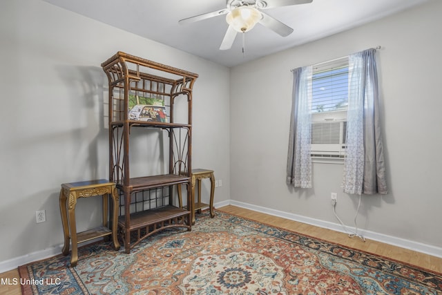 spare room featuring cooling unit, wood finished floors, baseboards, and ceiling fan