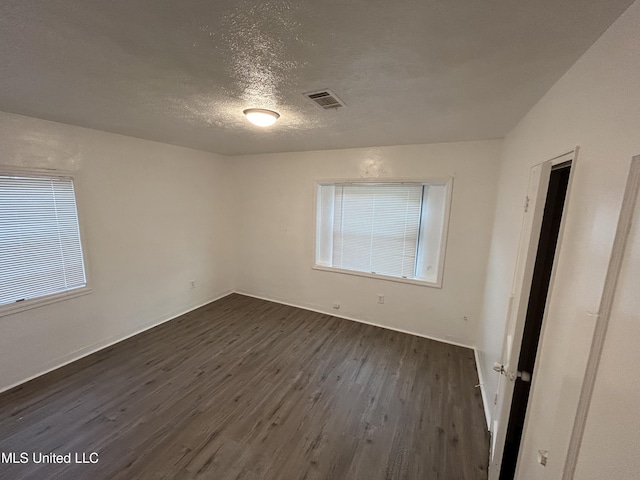 spare room with visible vents, dark wood-style flooring, and a textured ceiling