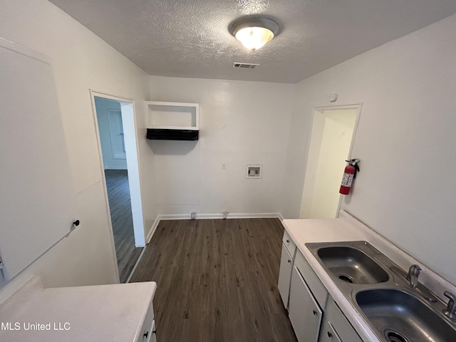 washroom with dark wood-style floors, a textured ceiling, washer hookup, visible vents, and a sink