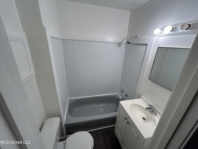 bathroom with toilet, wood finished floors, vanity, and shower / washtub combination