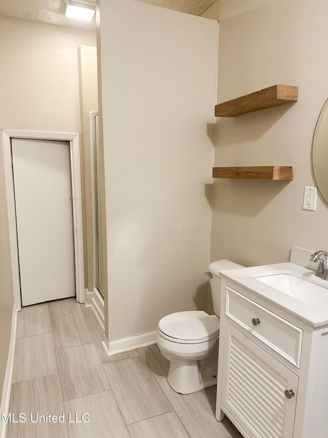 bathroom with vanity, toilet, and a shower with door