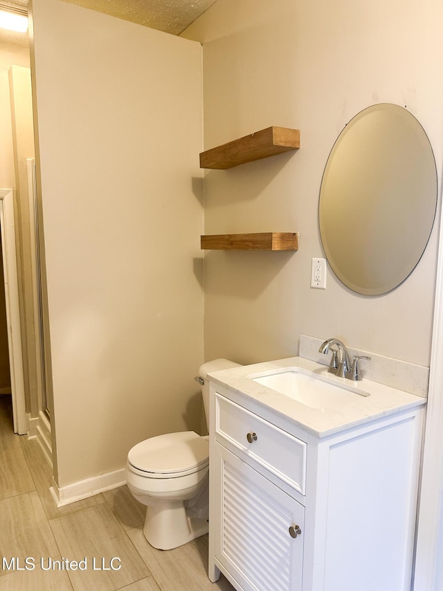 bathroom with hardwood / wood-style flooring, vanity, toilet, and a shower with shower door