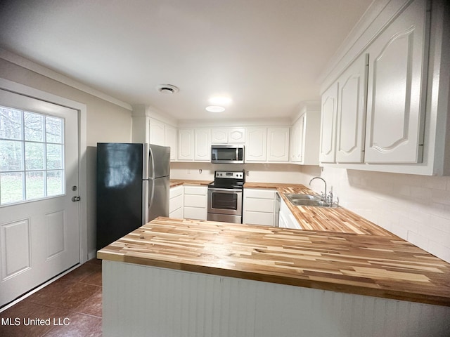 kitchen featuring sink, white cabinetry, wooden counters, kitchen peninsula, and stainless steel appliances