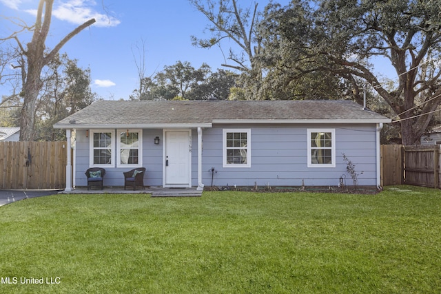 view of front of home with a shingled roof, fence, and a front lawn