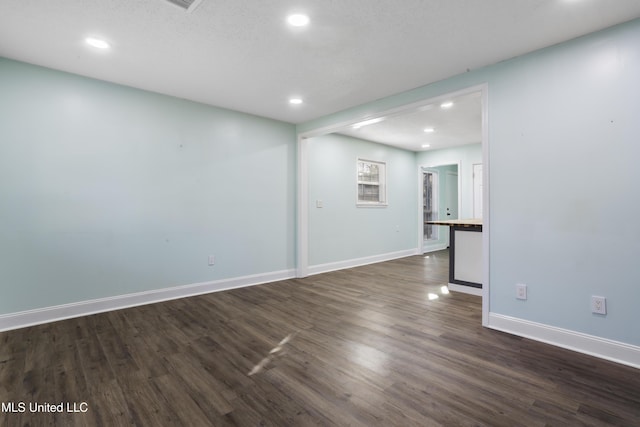 empty room featuring dark wood-type flooring, recessed lighting, and baseboards