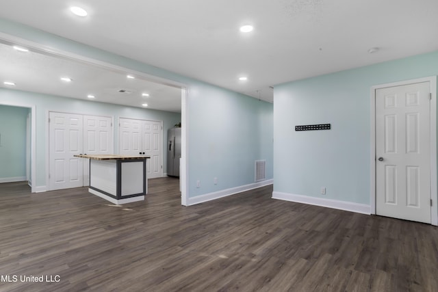 unfurnished living room with dark wood finished floors, visible vents, and baseboards