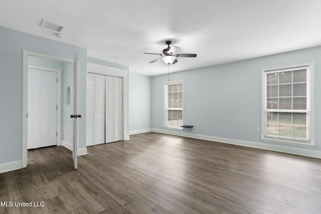 unfurnished bedroom featuring dark wood-style floors, a textured ceiling, and baseboards