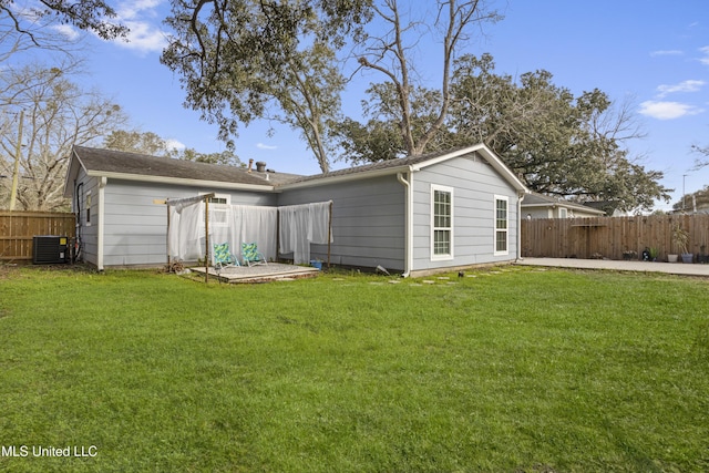 back of house with central air condition unit, fence, and a yard