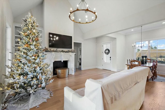 living room featuring high vaulted ceiling, an inviting chandelier, and light hardwood / wood-style flooring