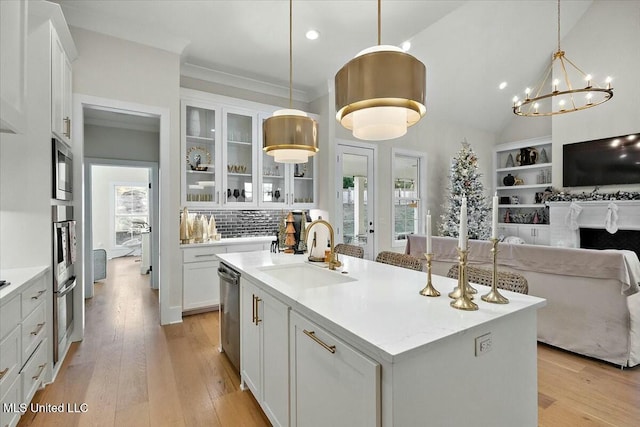 kitchen featuring a center island with sink, white cabinets, decorative light fixtures, and sink