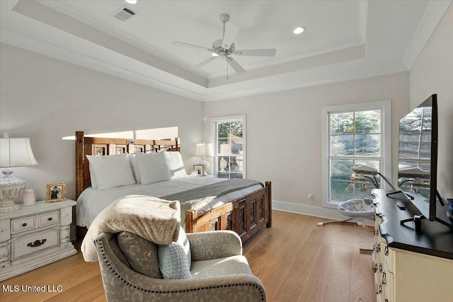 bedroom with a tray ceiling, multiple windows, ceiling fan, and light hardwood / wood-style floors