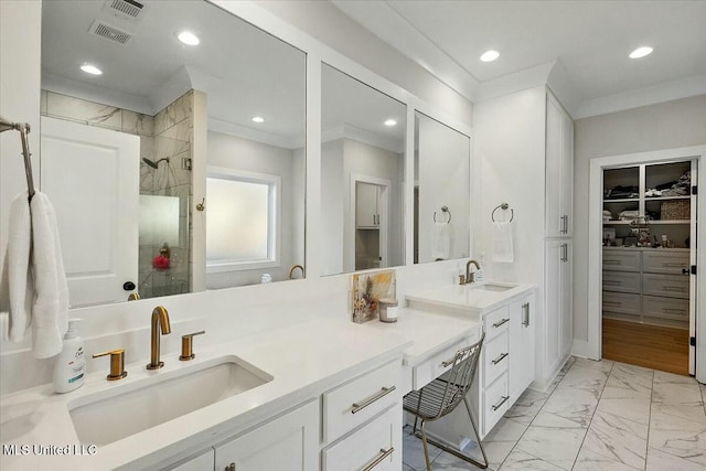 bathroom with tiled shower, vanity, and ornamental molding