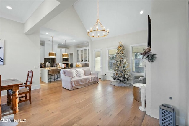 living room with a chandelier, high vaulted ceiling, and light hardwood / wood-style floors