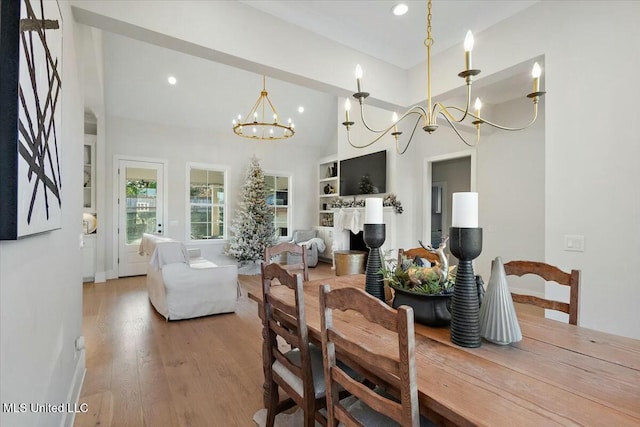 dining room featuring wood-type flooring, a towering ceiling, and a chandelier