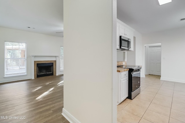 kitchen with light tile patterned floors, white cabinetry, and electric range oven