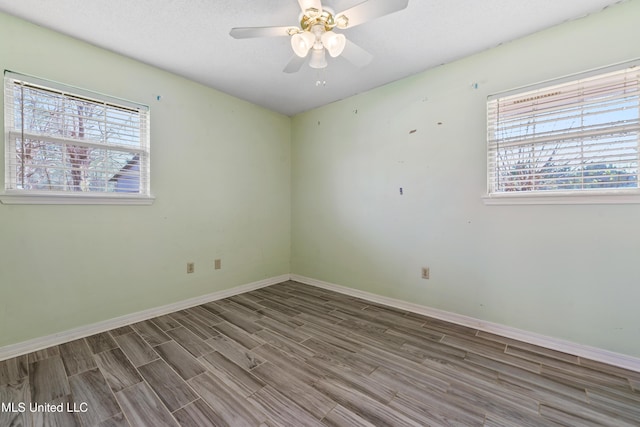 unfurnished room with wood finished floors, a ceiling fan, and baseboards