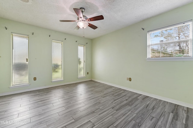 empty room featuring wood finished floors, a ceiling fan, baseboards, and a textured ceiling