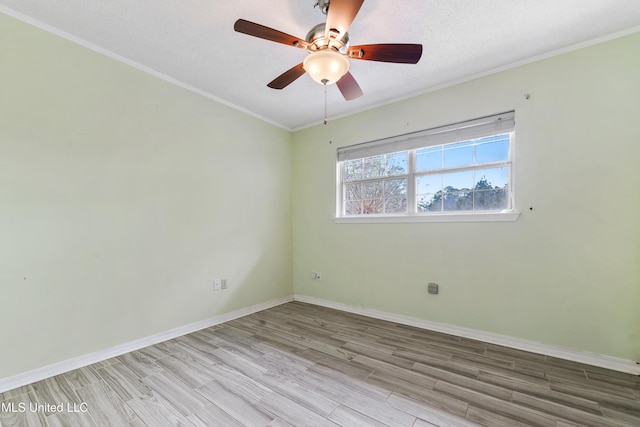 empty room featuring wood finished floors, baseboards, ornamental molding, ceiling fan, and a textured ceiling