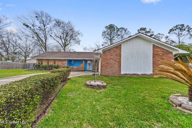 mid-century inspired home featuring concrete driveway, fence, brick siding, and a front yard