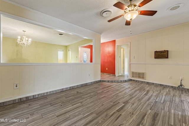 spare room with visible vents, ceiling fan with notable chandelier, a textured ceiling, and wood finished floors