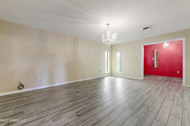 unfurnished room featuring a notable chandelier, a textured ceiling, and wood tiled floor