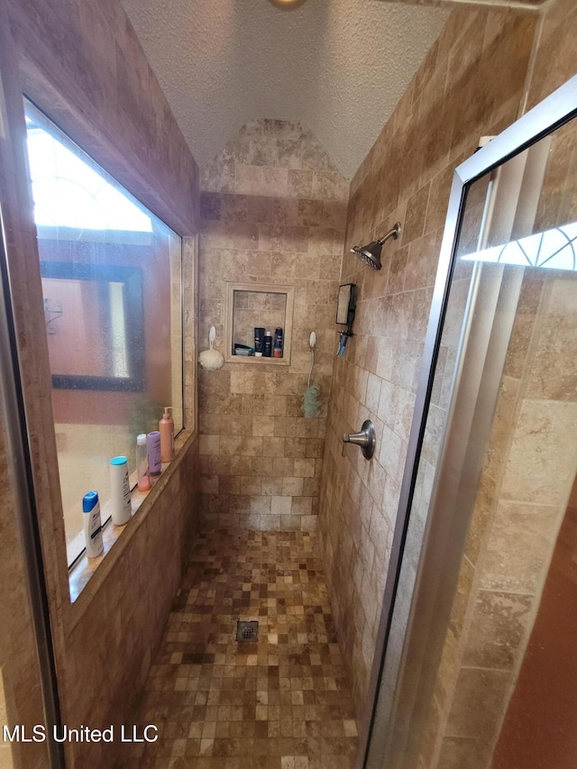 8475 Windersgate Dr, Olive Branch, MS 38654 - bathroom with a tile shower, vaulted ceiling, and a textured ceiling