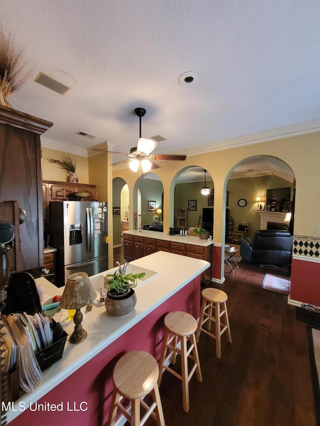 8475 Windersgate Dr, Olive Branch, MS 38654 - kitchen with stainless steel refrigerator with ice dispenser, arched walkways, a peninsula, ornamental molding, and a breakfast bar